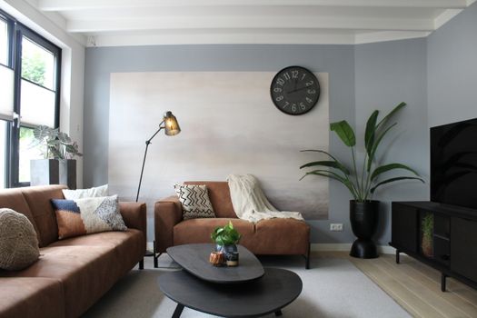 Sfeervolle woonkamer met aardetinten, vintage meubel en chromen lamp volgens de interieurtrends van 2026 in Wijchen