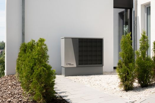 Buitenunit van een warmtepomp naast een duurzaam huis in Wijchen